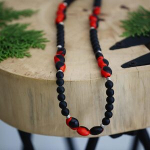 Stylish handmade bead necklace displayed elegantly on a natural wooden surface with greenery.