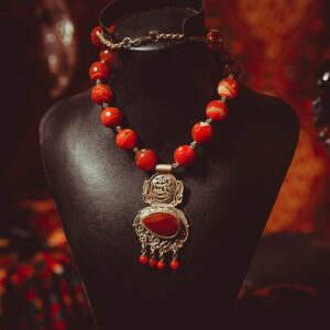 Luxurious red beaded necklace with intricate pendant on a display bust in a warm setting.