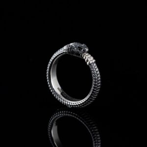 Close-up of a silver snake-themed ring with reflection on a black background.