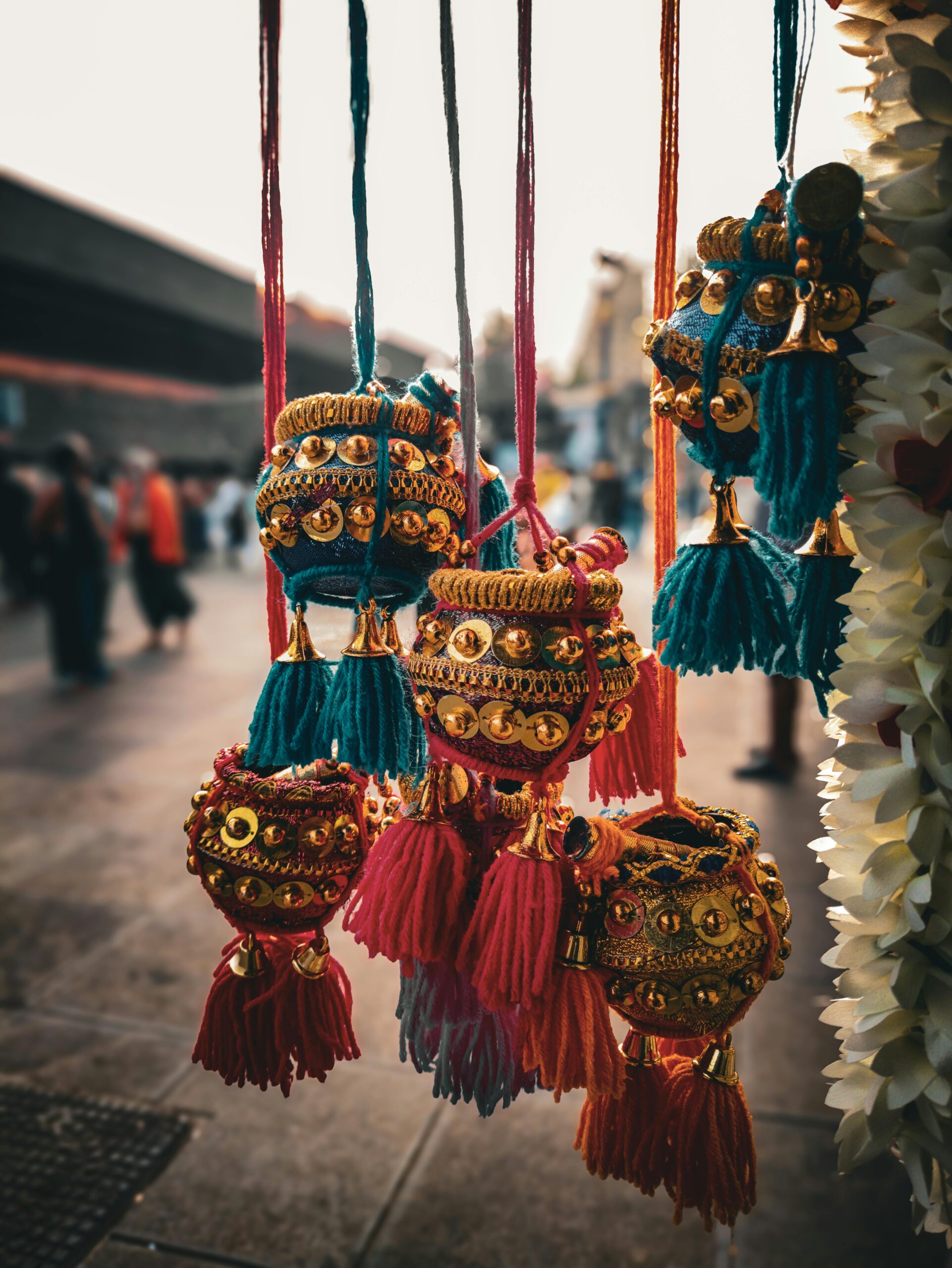 About Vibrant traditional tassels with intricate embellishments in an outdoor market setting.