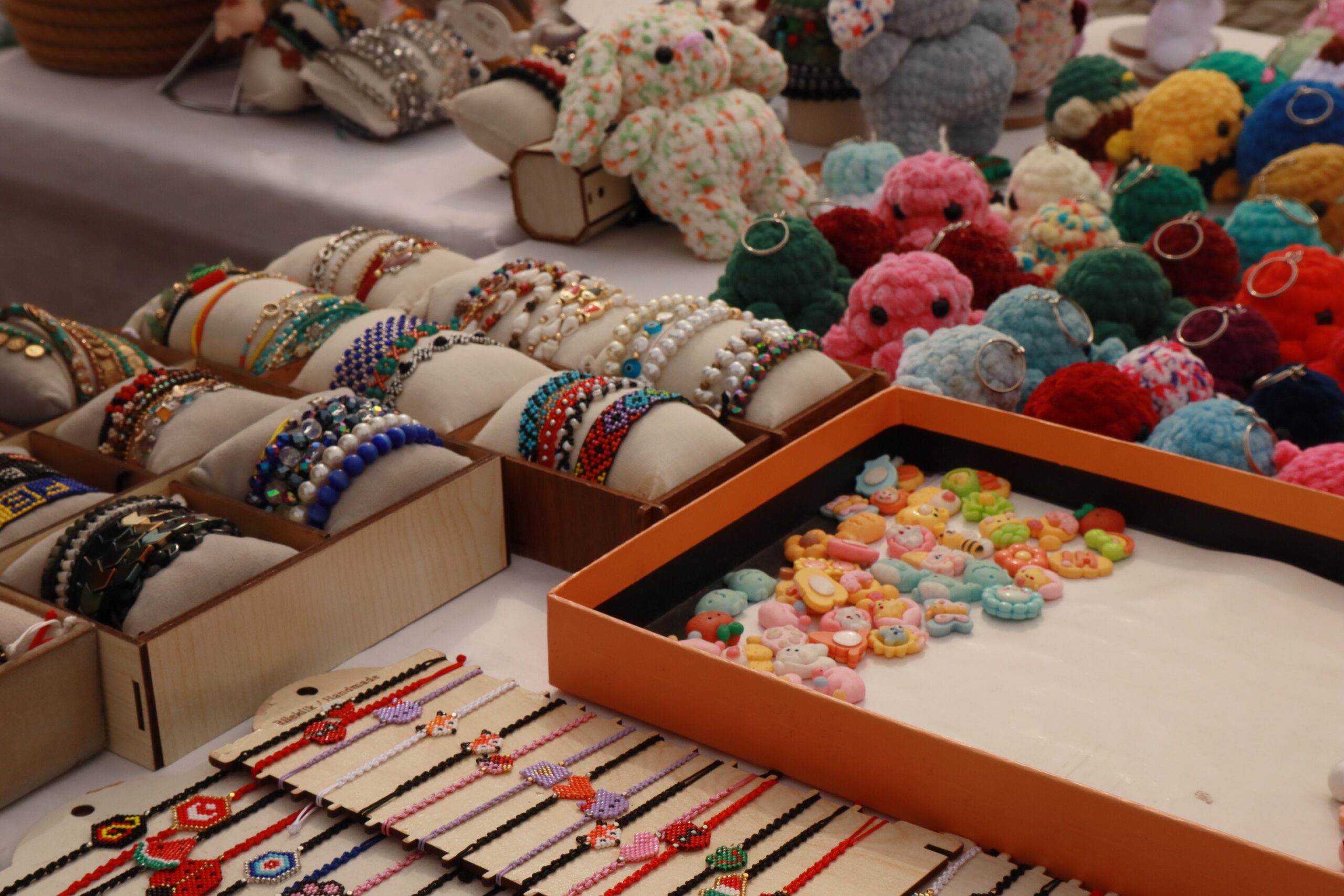 About Vibrant display of handmade bracelets and crocheted keychains at a market stall.